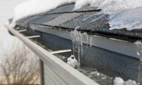 close view of roof eave and gutter with ice and snow