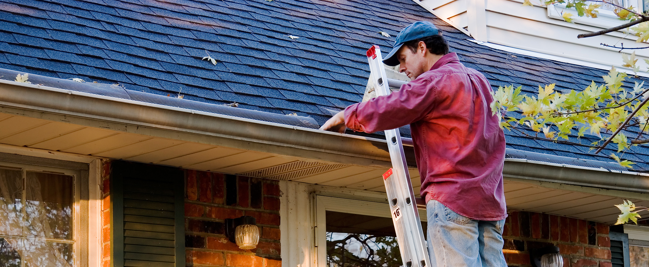 Man inspecting asphalt shingle roof for seasonal maintenance.