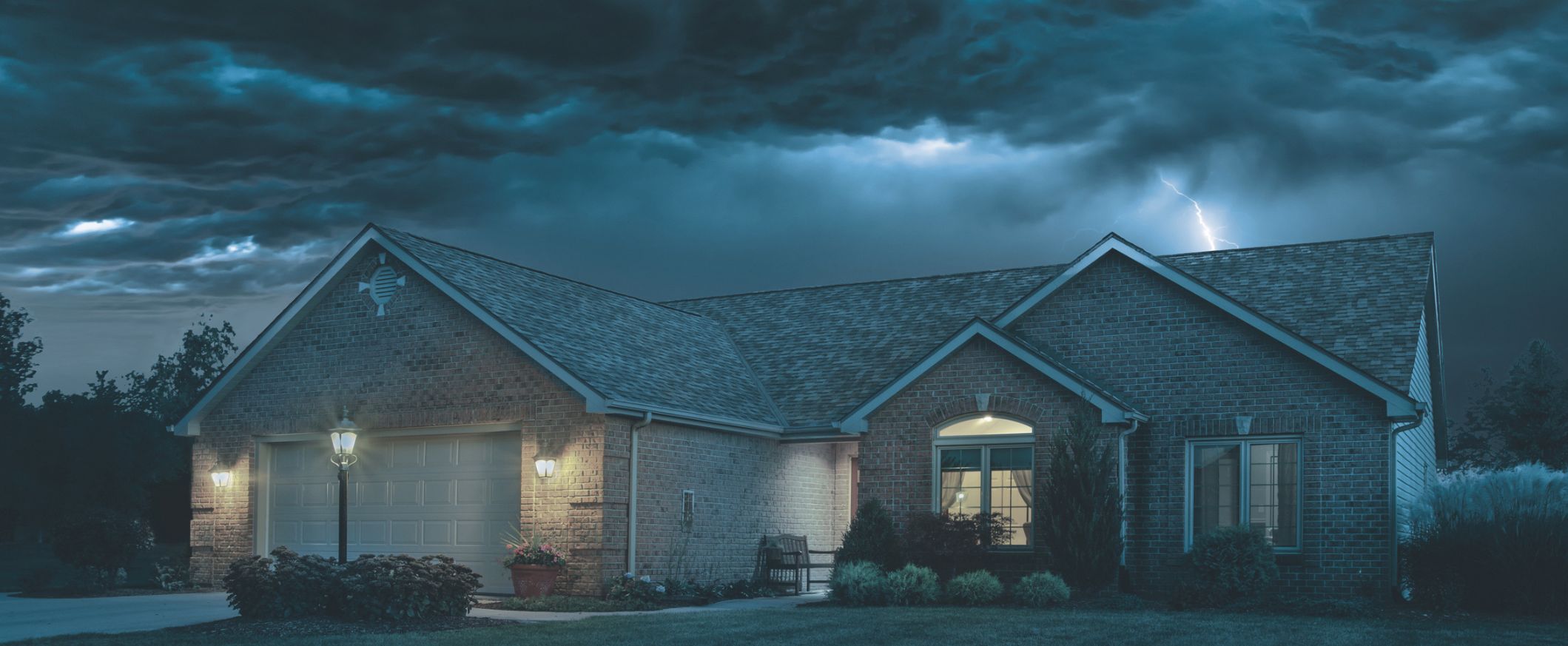 Dark storm clouds and lightning striking above a residential home, representing natural disaster threats like severe storms.