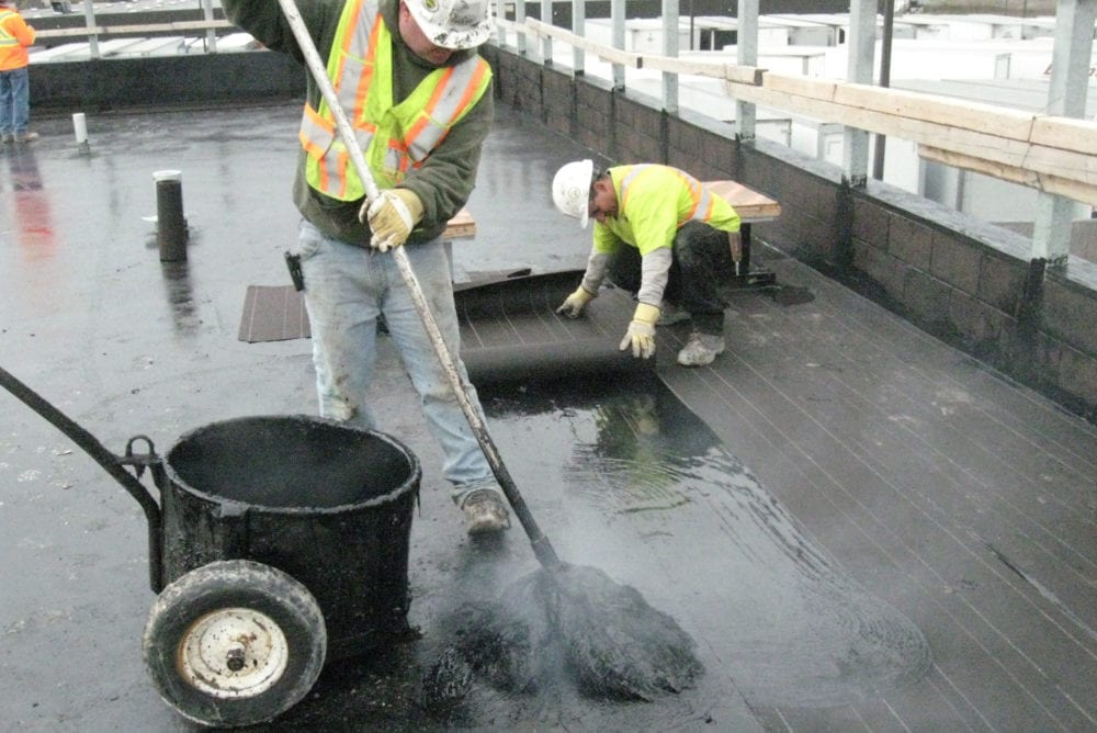 Roofer hot mopping Asphalt Type 1 on a roof
