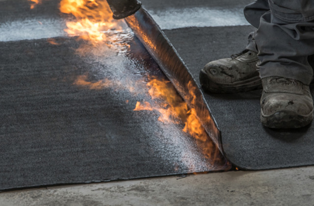 close up of a roofer torching down a membrane