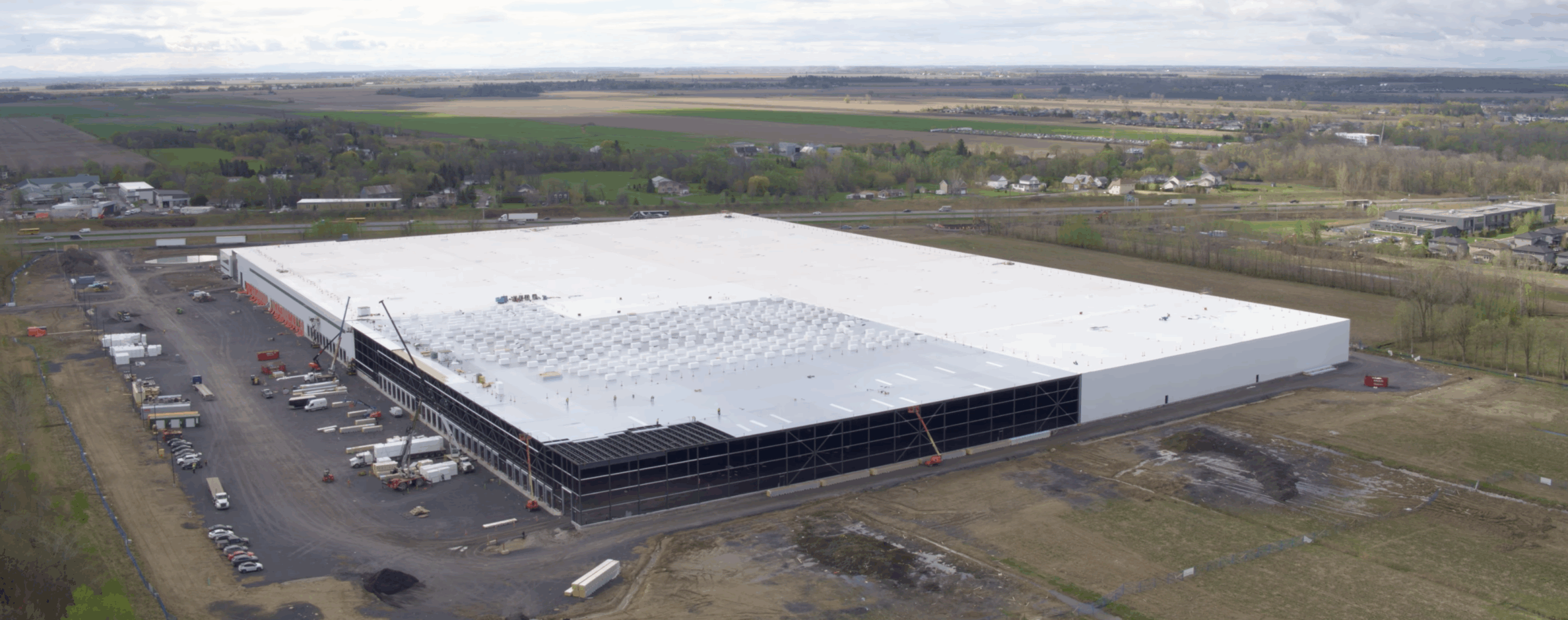 A large commercial building development with TPO roofing membrane being installed over bay doors.