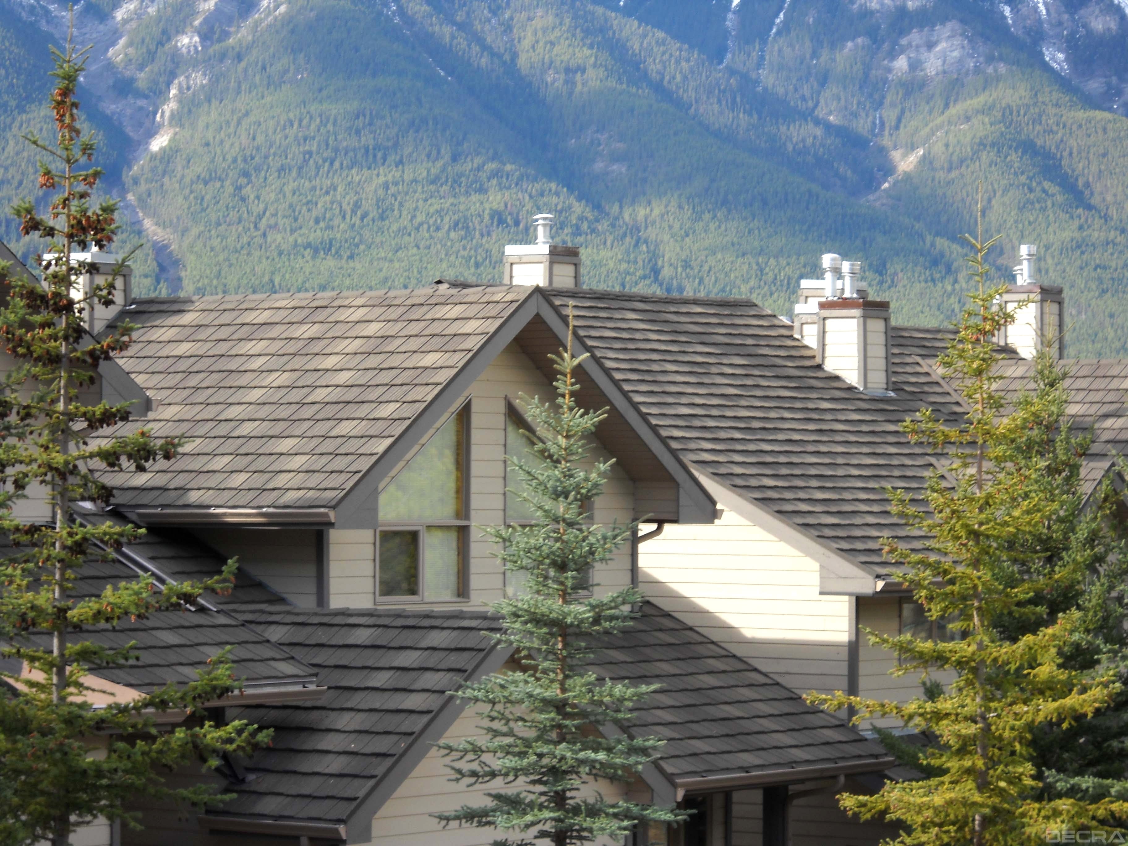DECRA shake-profile metal roof on a mountain home with pine trees and forested peaks in the background