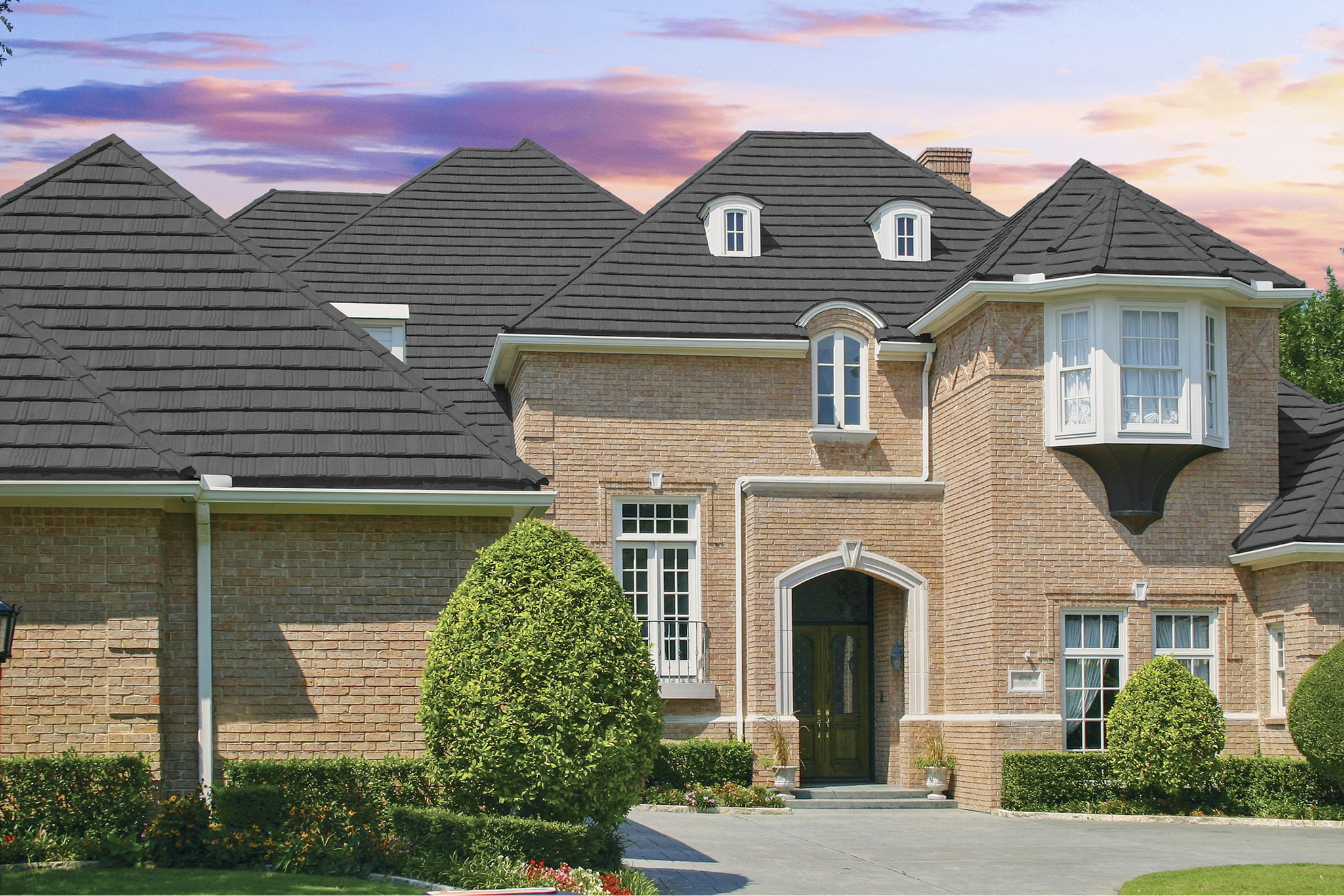 DECRA Farmhouse Shake roof in Country Millstone on brick luxury home with dormers and manicured landscaping at sunset