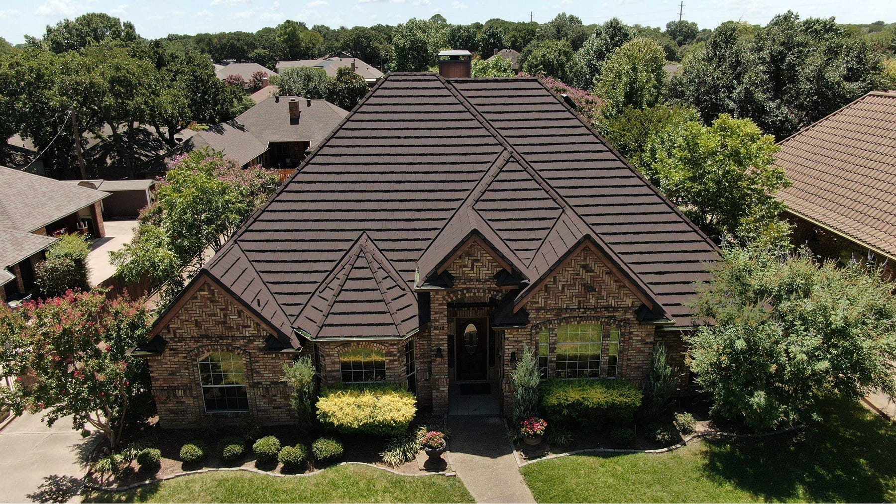 DECRA Farmhouse Shake Heritage Stone metal roof on brick home, stone-coated panels with shake texture and strong curb appeal