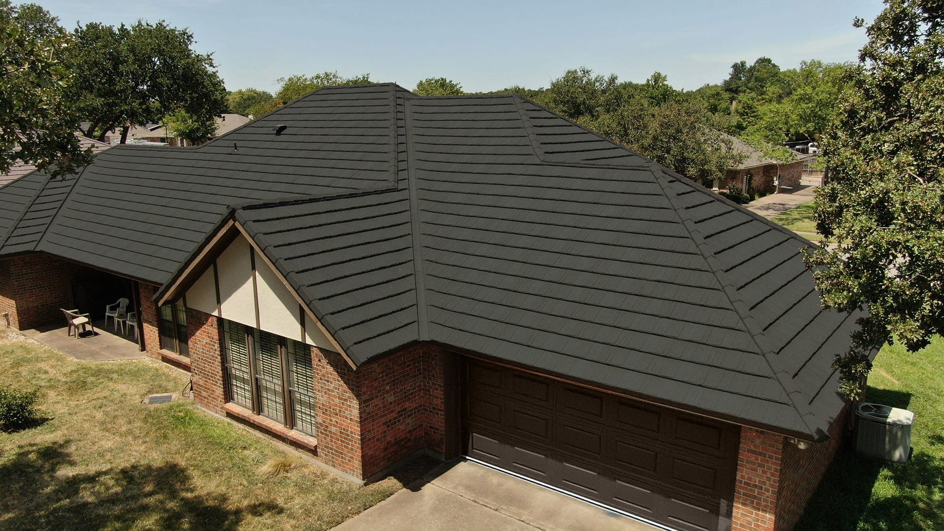 DECRA Farmhouse Shake Timber Green stone-coated steel roof on a brick home, showing cedar-like grain, shadow lines and ridges