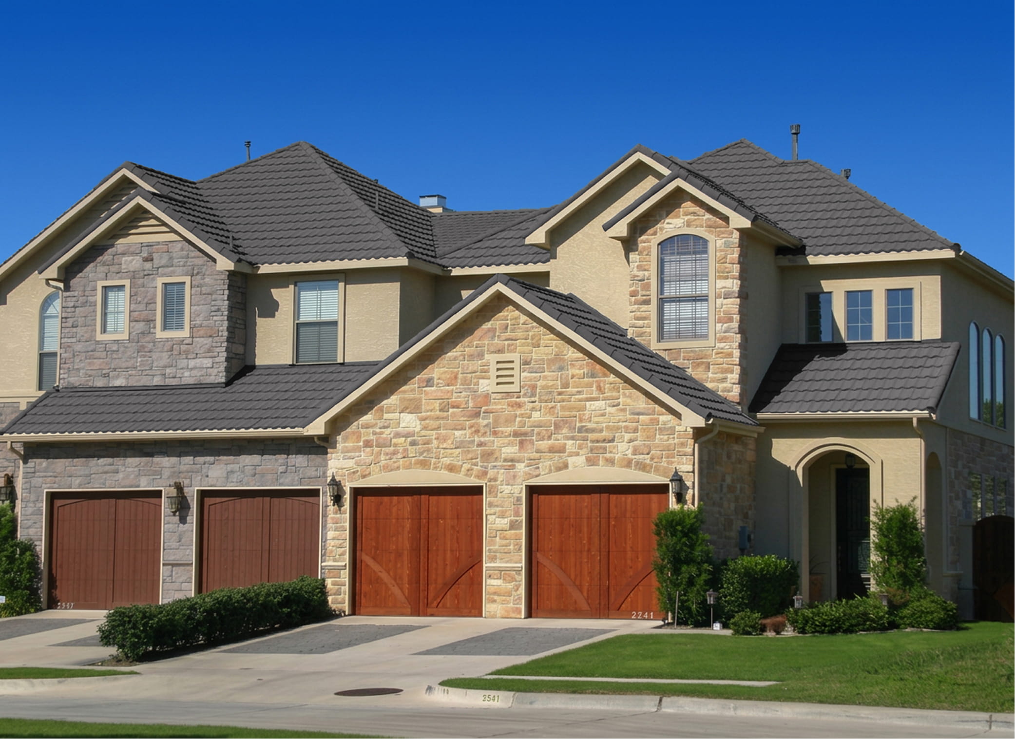 DECRA Mediterranean Tile Cathedral Stone stone-coated steel roof on a home with stone facade, stucco walls and arched windows