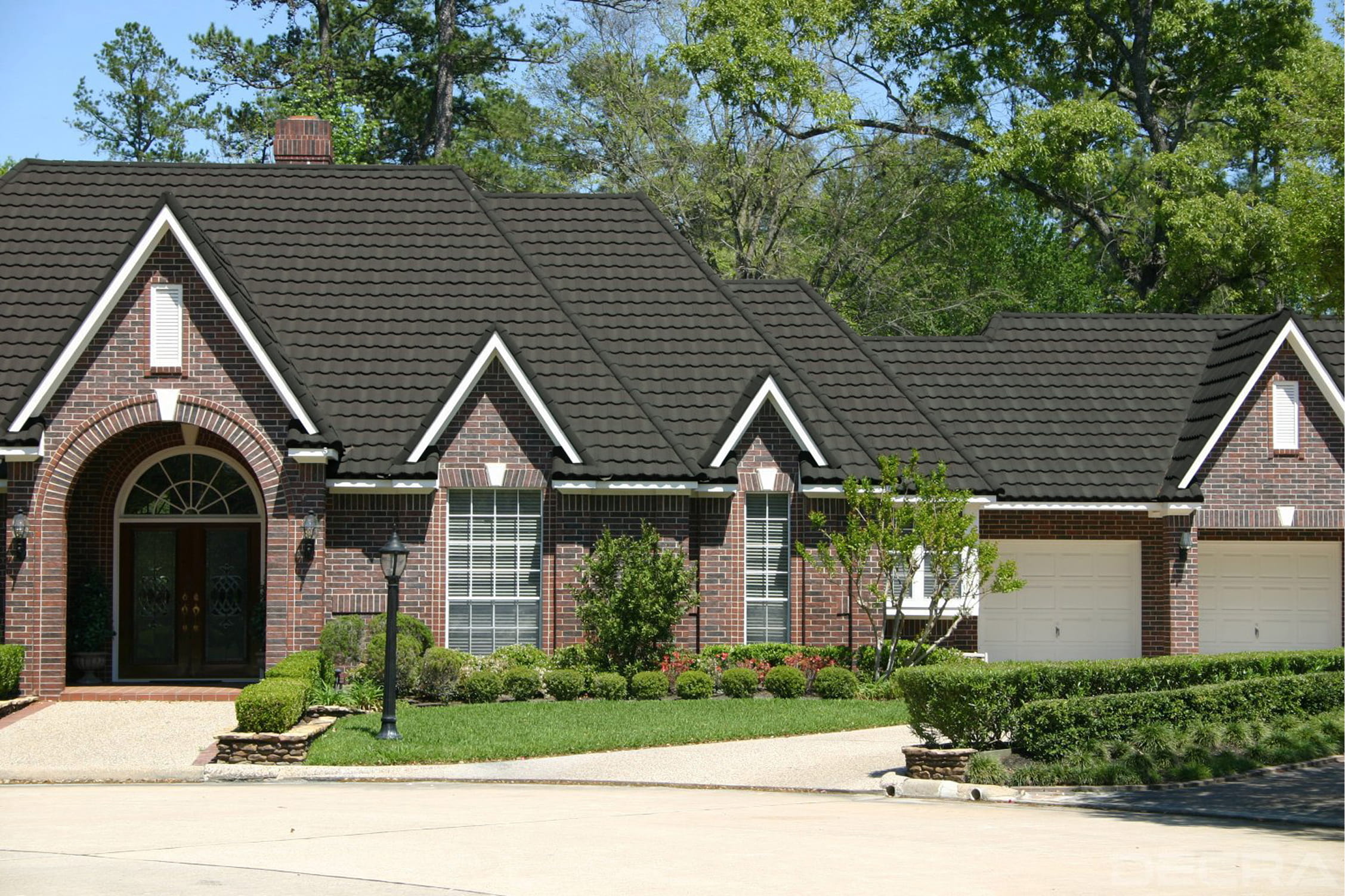 DECRA Mediterranean Tile in Woodland Pine installed on brick house emphasizing stone-coated steel durability and style