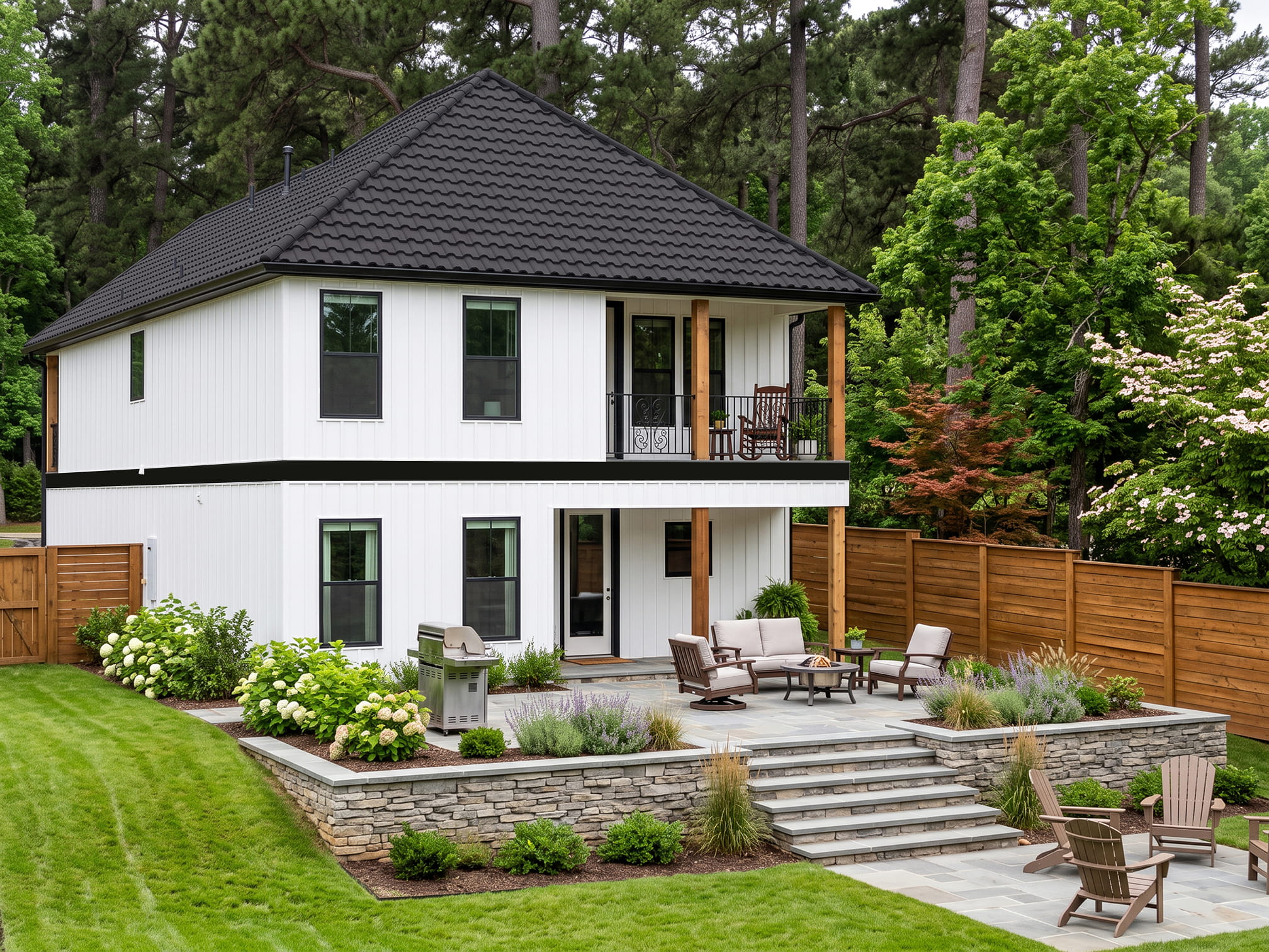 DECRA Spanish Tile in Carbon on a modern two-story white home with landscaped yard, patio seating and stone retaining wall