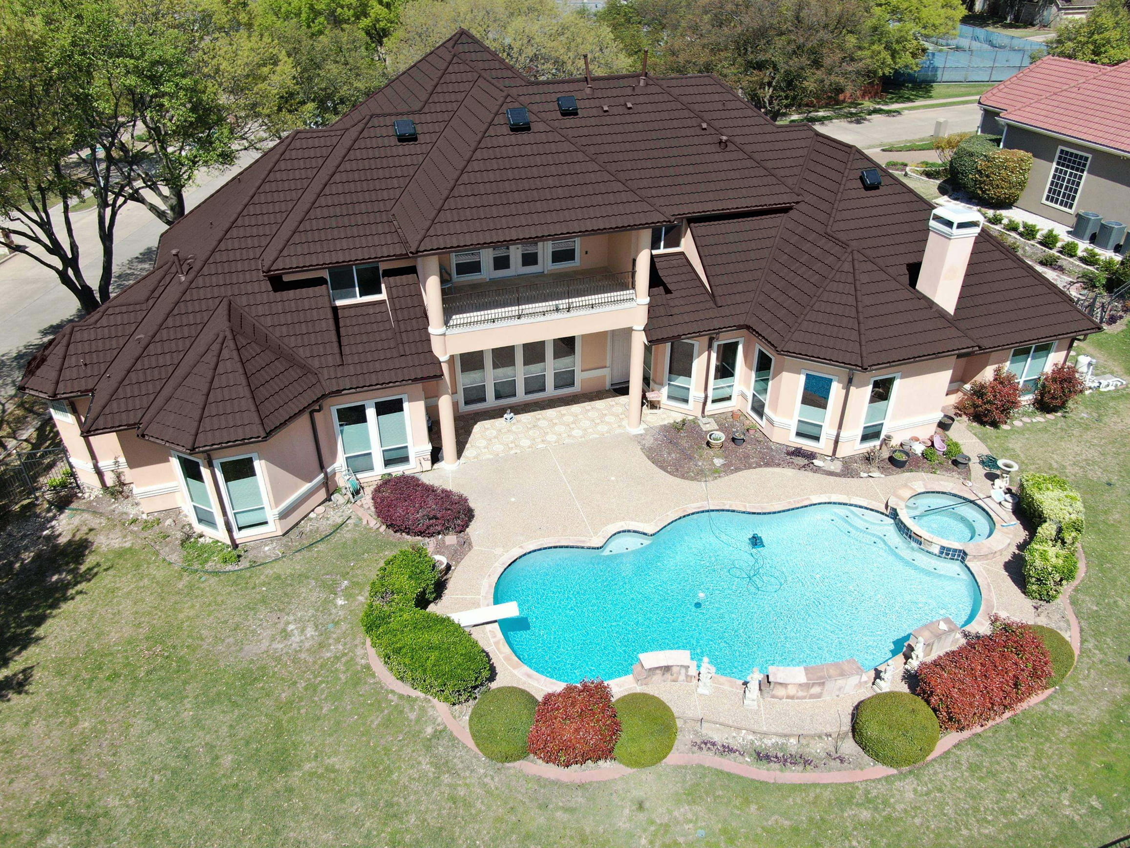 Aerial shot of DECRA Mediterranean Tile in Ironwood on a large home, highlighting stone-coated steel texture by the pool