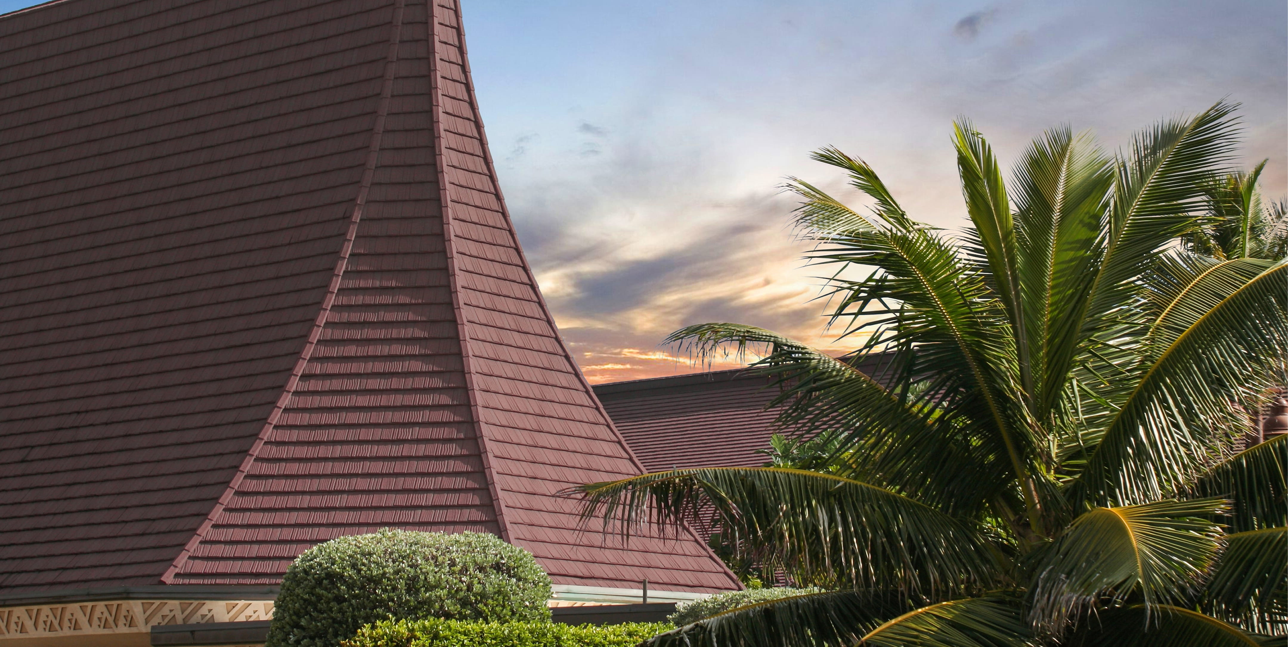 DECRA metal shake roof in rich brown on a steep pavilion peak with tropical palm trees and sunset sky backdrop