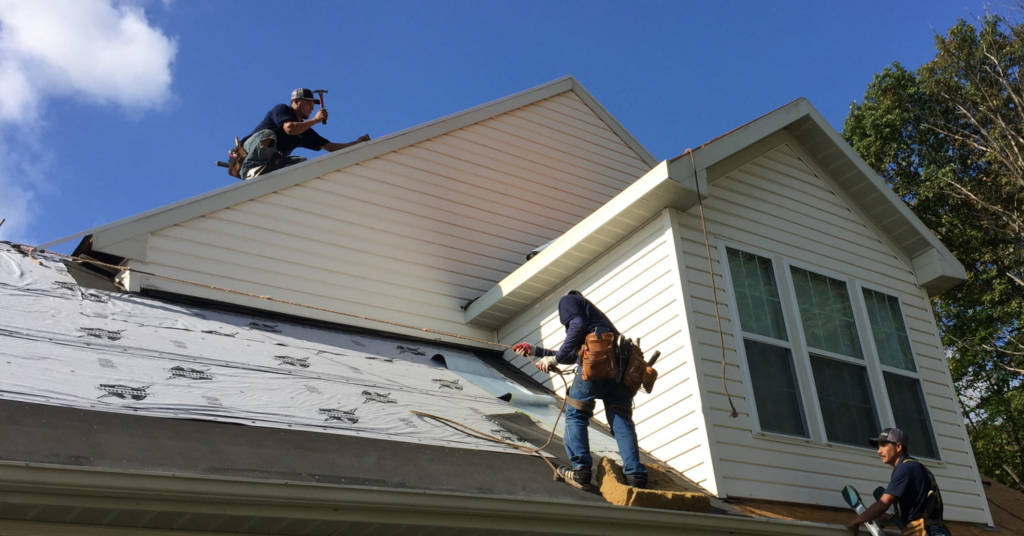 Roofers installing underlayment on a roof.