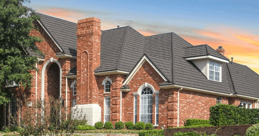 Mediterranean Scalloped Tile Carbon stone-coated steel roof on brick home, low-profile scalloped tiles at dusk