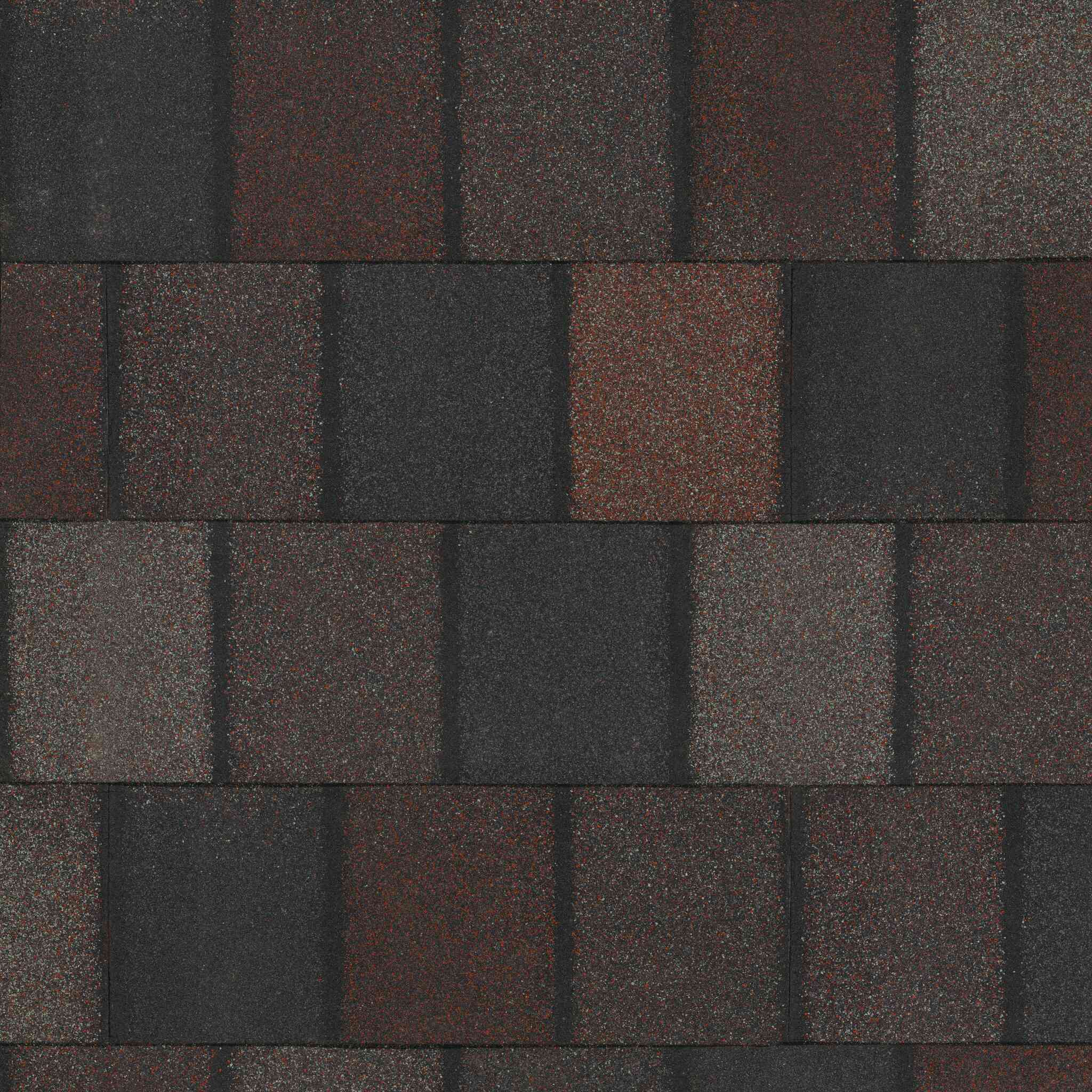 Primer plano de un techo de tejas asfálticas con piezas oscuras y marrón rojizo apagado alternadas en un patrón rectangular, que recuerda Crowne Slate.