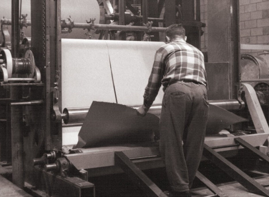 Un trabajador opera una máquina cortadora de papel y ajusta con precisión la alineación de las hojas, con una exactitud propia de la tecnología avanzada.