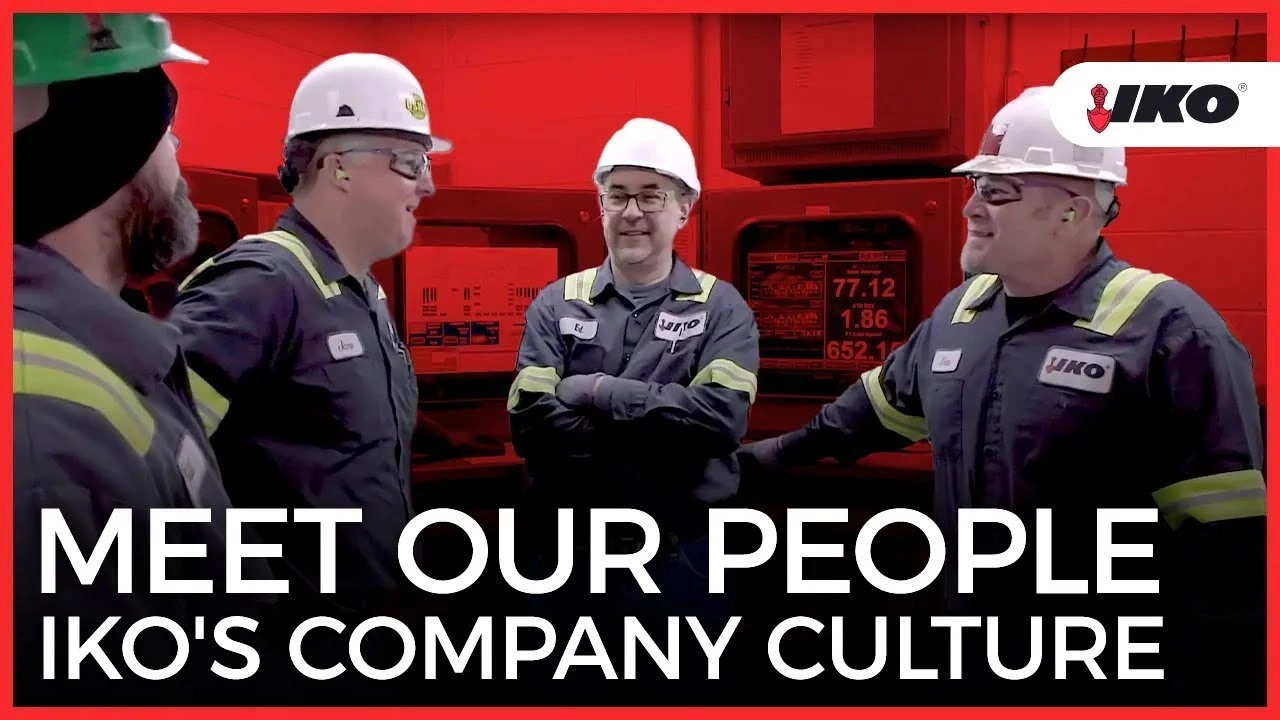Four workers in safety gear converse in a factory setting under a red overlay, embodying the essence of IKO Company Culture. The text reads, "Meet Our People.