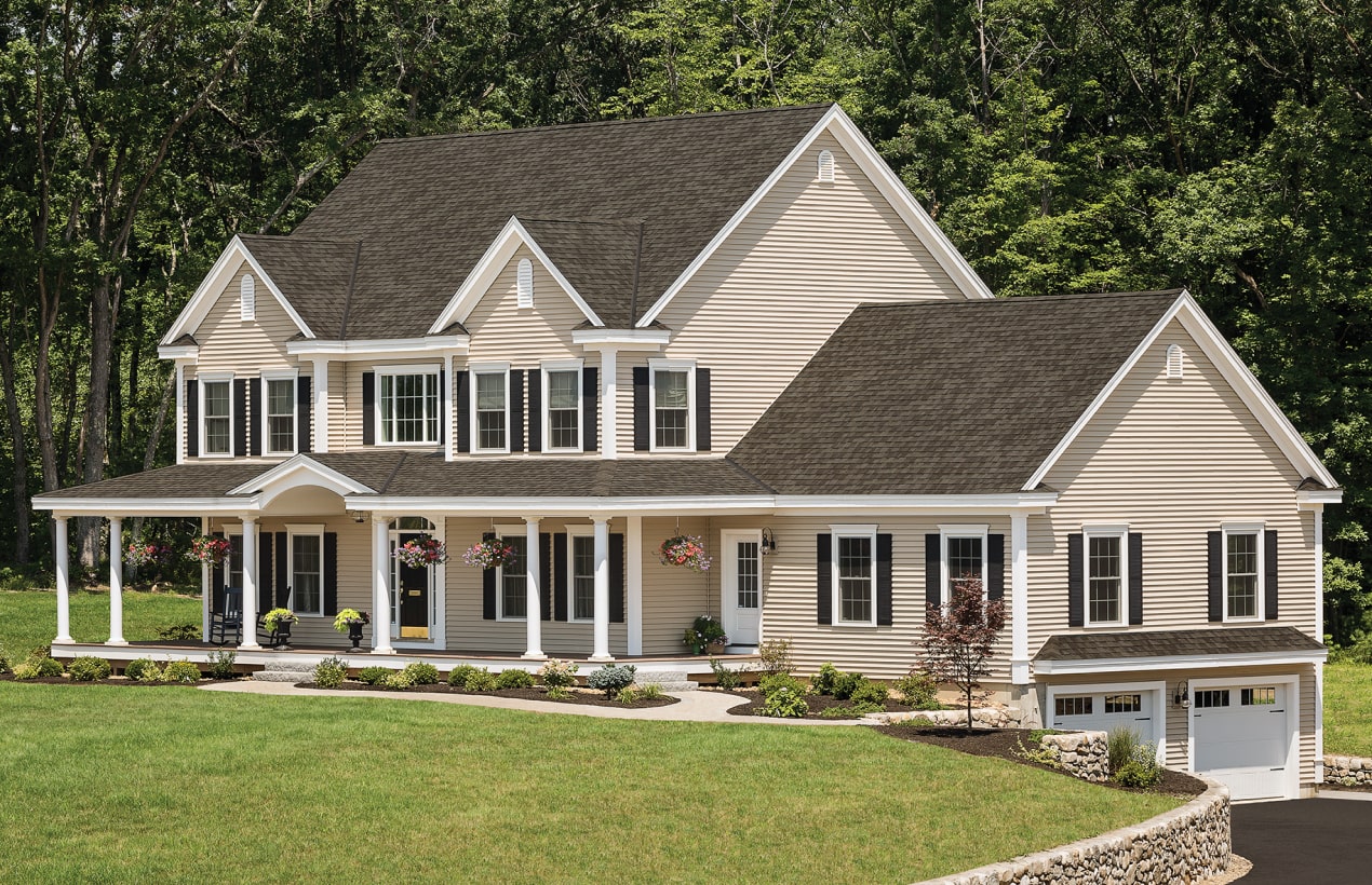 Two-story beige home with a covered porch, black shutters and a brown shingle roof