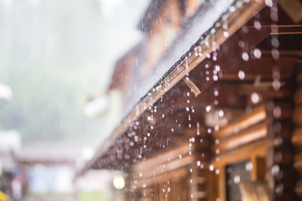 water dripping from wood cottage shingle roof under heavy rain