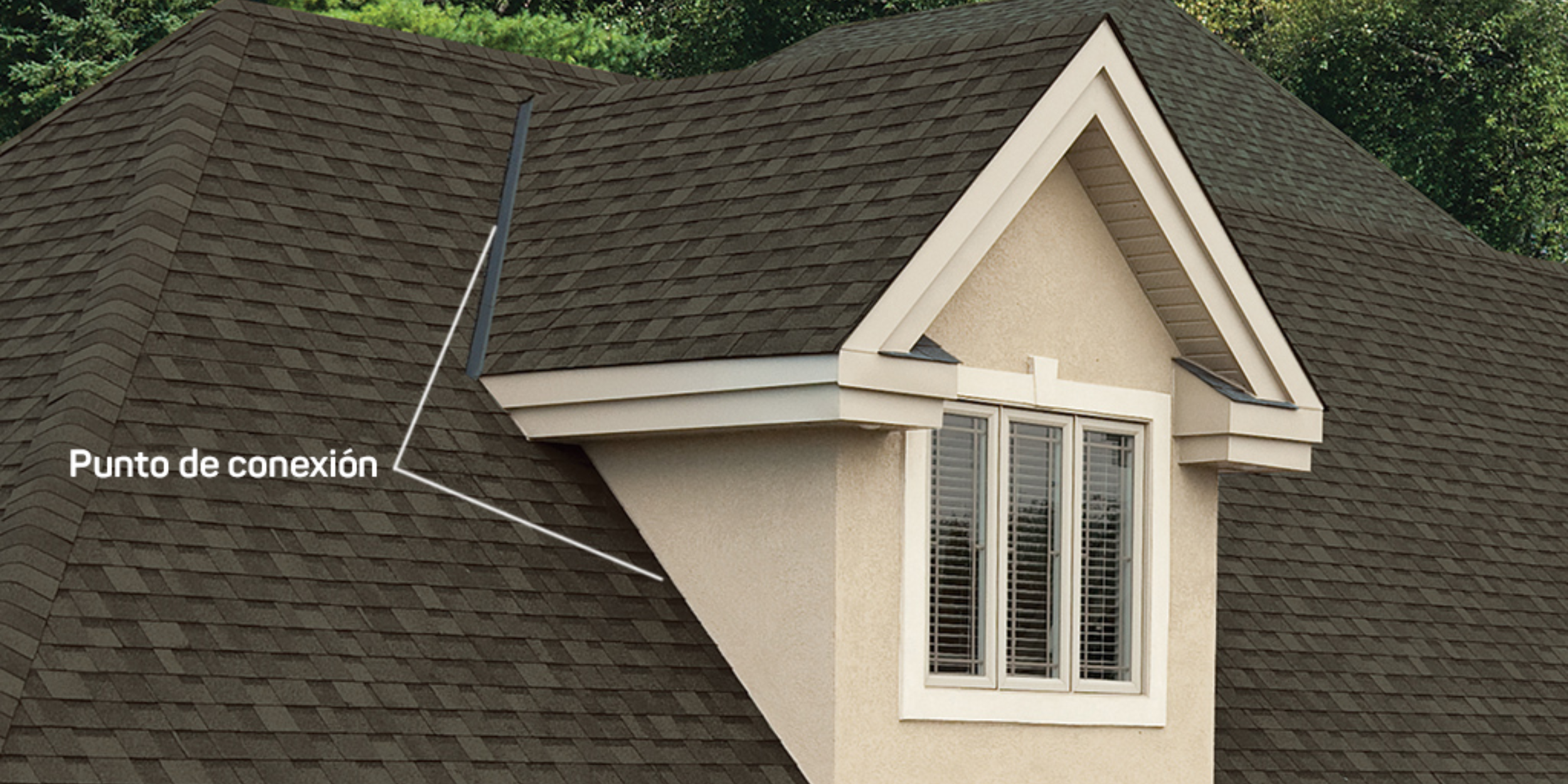 Un primer plano de una buhardilla a dos aguas que muestra el "punto de conexión" donde la limahoya de la buhardilla se une con el techo principal, ilustrando un área que requiere un tapajuntas adecuado.