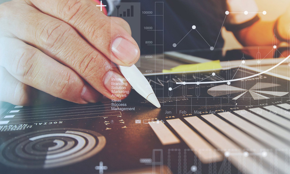 Hand holding a stylus over a tablet showing business charts and graphs with words like Branding, Marketing and Success