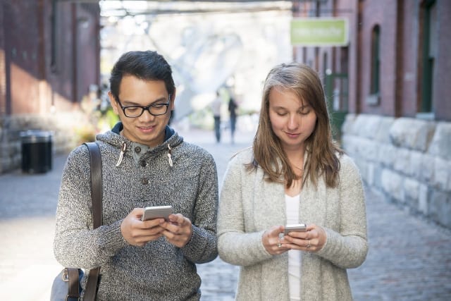 man and woman looking at their smartphones