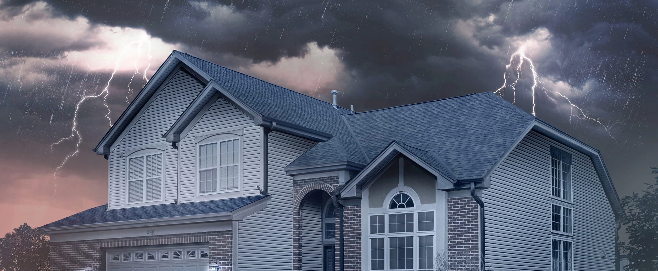 Des nuages d’orage accompagnés d’éclairs planent au-dessus d’une grande maison dotée d’une toiture IKO.