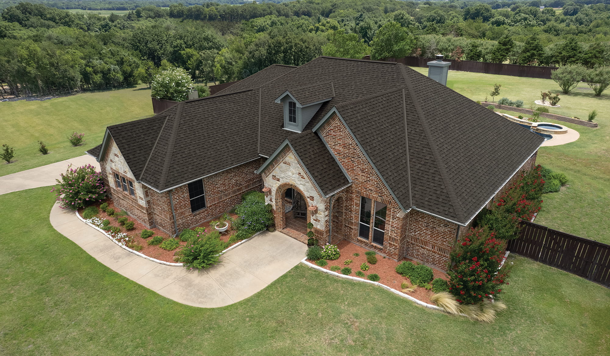 Brick and stone house with a new dark brown architectural shingle roof, seen from above