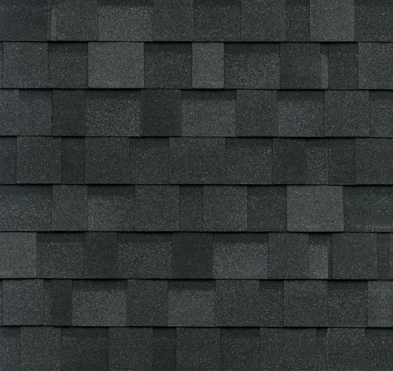 Gros plan d'un motif de toiture en bardeaux d'asphalte verts texturés, aux bardeaux rectangulaires disposés uniformément, subtilement rehaussés de touches de teintes granite.