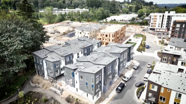 Une personne aux cheveux courts et à la barbe, au léger sourire, regarde la caméra dans une pièce aux murs clairs et à la porte de bois. Les avantages de choisir ROOFPRO pour vos projets sont aussi évidents que l'ambiance chaleureuse de cet espace accueillant.