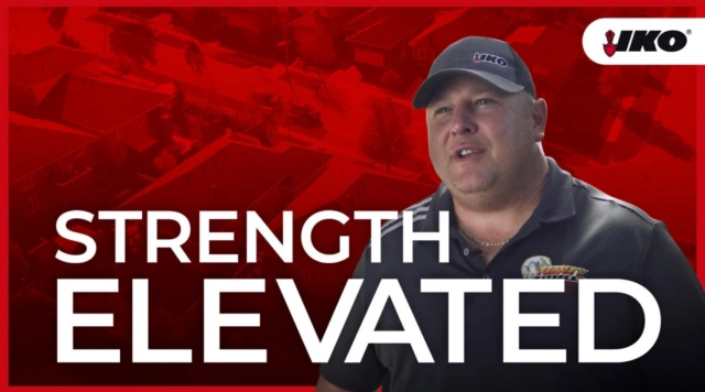 Un hombre con gorra y camisa polo está de pie con seguridad frente a una vista aérea roja de un vecindario, con «Strength Elevated» y el logotipo de IKO bien visibles, un testimonio genuino del compromiso de Feeney Roofing con la calidad.