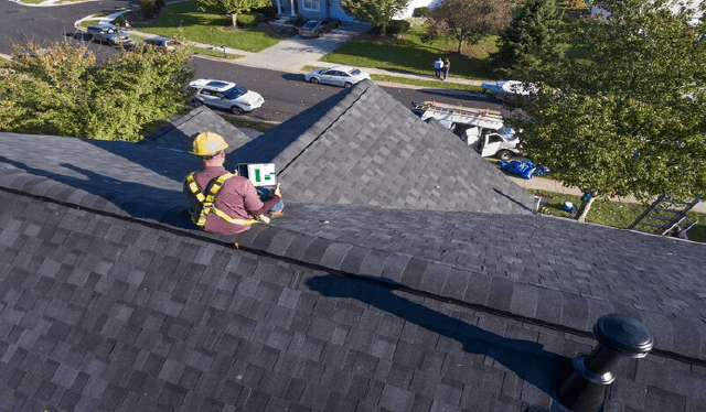 roofer on top of a shingled roof
