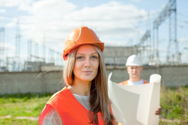 woman and man wearing hard hats and looking at site plans