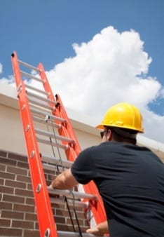 man climbing up a ladder to get to the roof