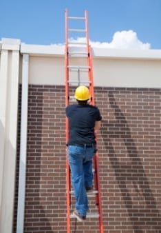 man using a ladder to climb up to a roof