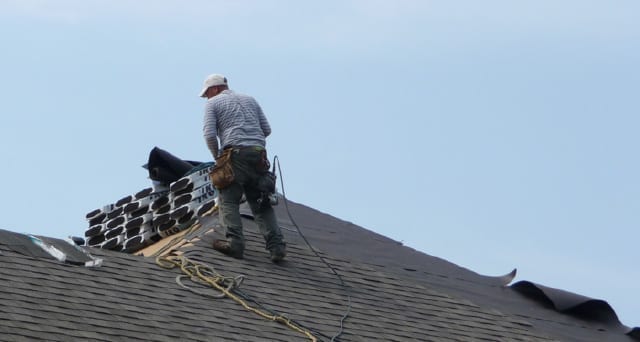 As a roofer, use good technique. A photo of a roofer on top of a roof with a safety harness.