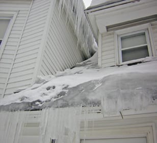 large ice dam and icicles coming down a residential roof during cold winter months