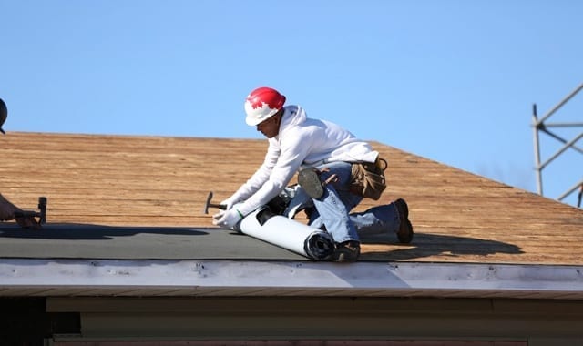 roofer installing roofing felt on a roof's deck