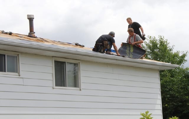 roofers installing rolling out a membrane on a roof
