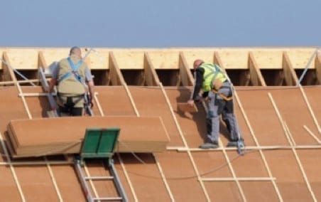 roofers instealling sheathing on a roof