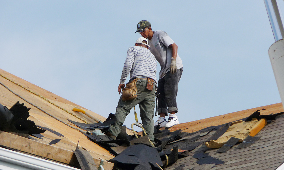 two roofers doing a tear off on a roof