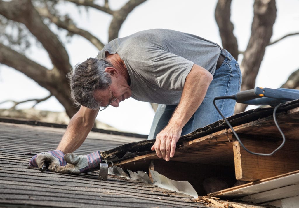 Man Examining roof slopes intersection in order to locate and repair a roof leak