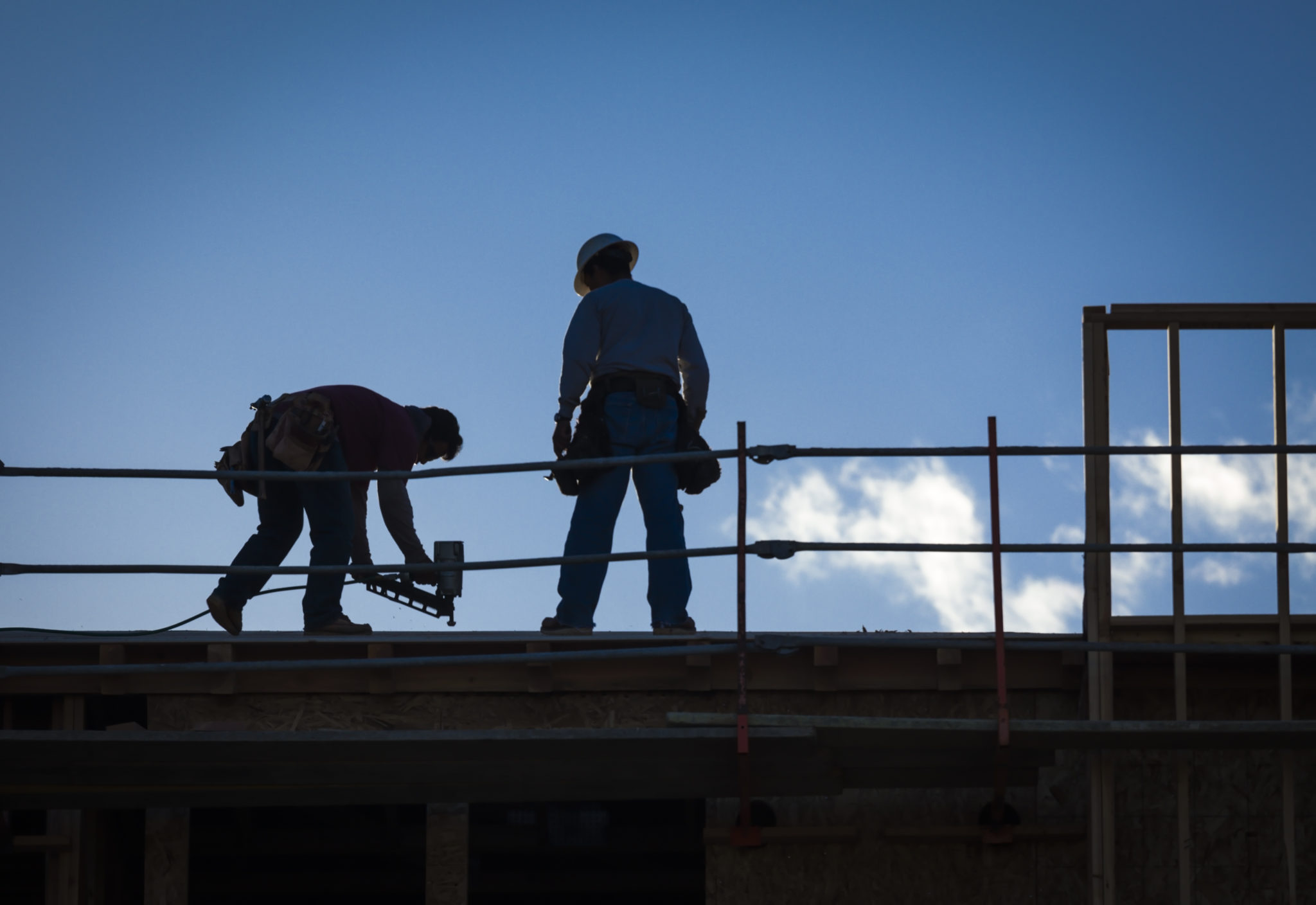 dos trabajadores de la construcción usando una pistola de clavos en un sitio de trabajo