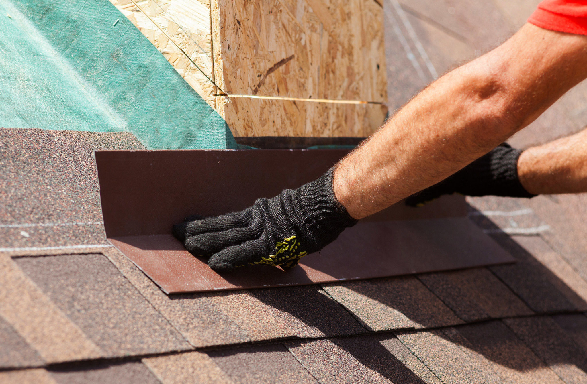 roofer adding flashing piece to a shingle roof