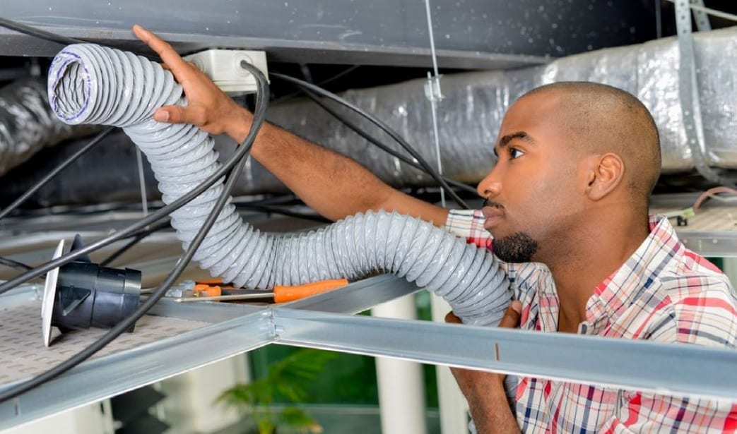 worker installing exhaust duct in a ceiling