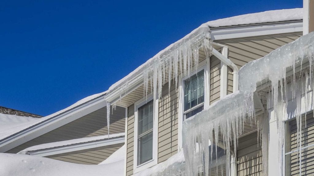 snow covered roof and icicles formed over gutters