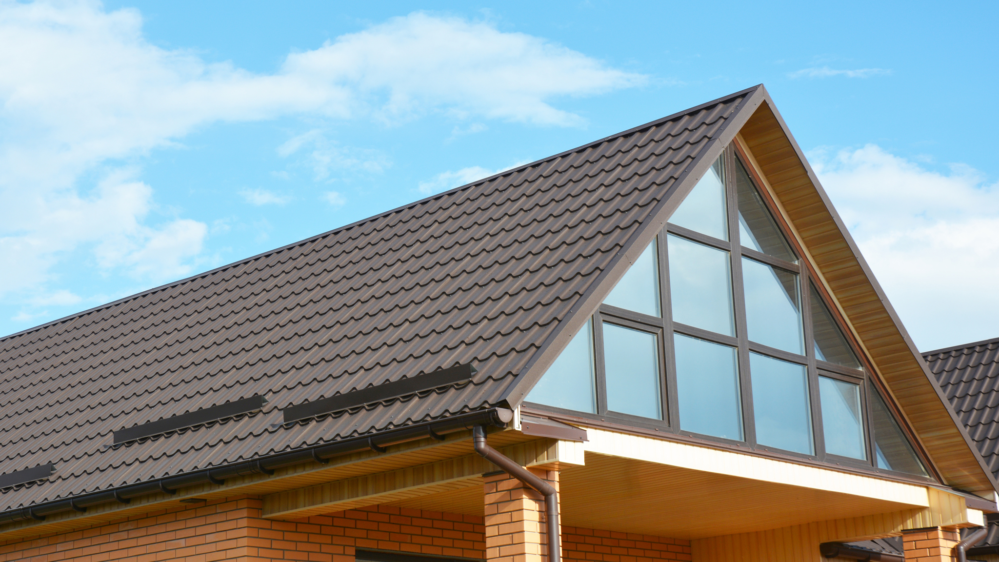 sloped roof with brown stamped metal roof panels simulating a clay tile appearance