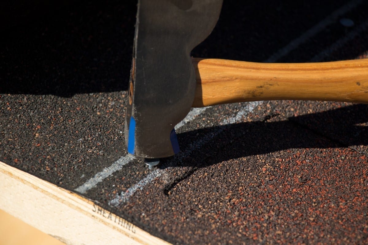 roofing nail being hammered through shingle during installation