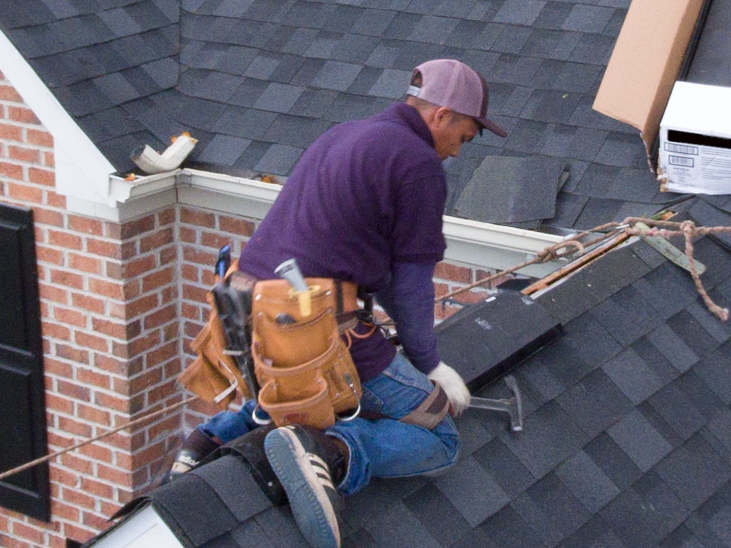 roofer using a roofing hatchet to install ridge cap shingles