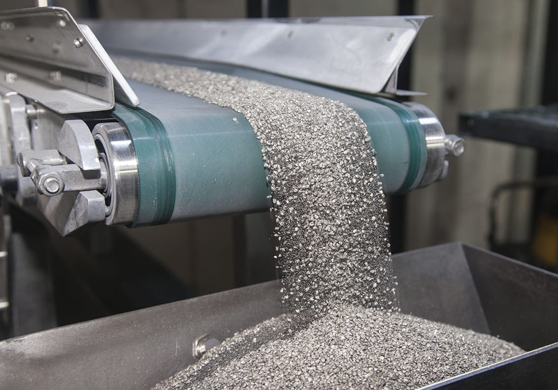 colored roof granules falling off the end of a conveyor belt