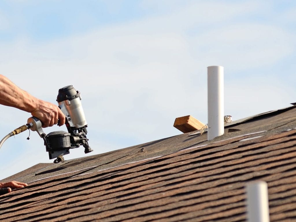 pipe stack vent next to a roofer shingling a roof